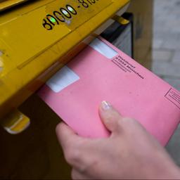 Briefwahlunterlagen werden in Briefkasten gesteckt.